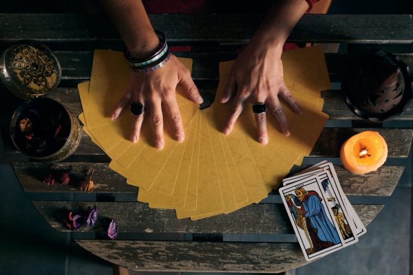 close-up-of-a-fortune-teller-displaying-some-tarot-cards-on-a-wooden-table